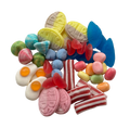 A colorful assortment of Swedish gummy and hard candies piled together on a plain white background, including pink striped pieces, red translucent gummies, blue pieces, yellow pieces, green and orange pieces, and egg-shaped white candies with orange yolks.